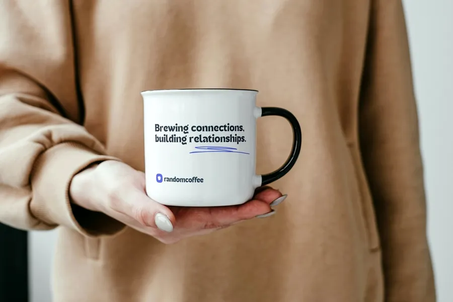A person holding a RandomCoffee mug with the tagline Brewing connections, building relationships