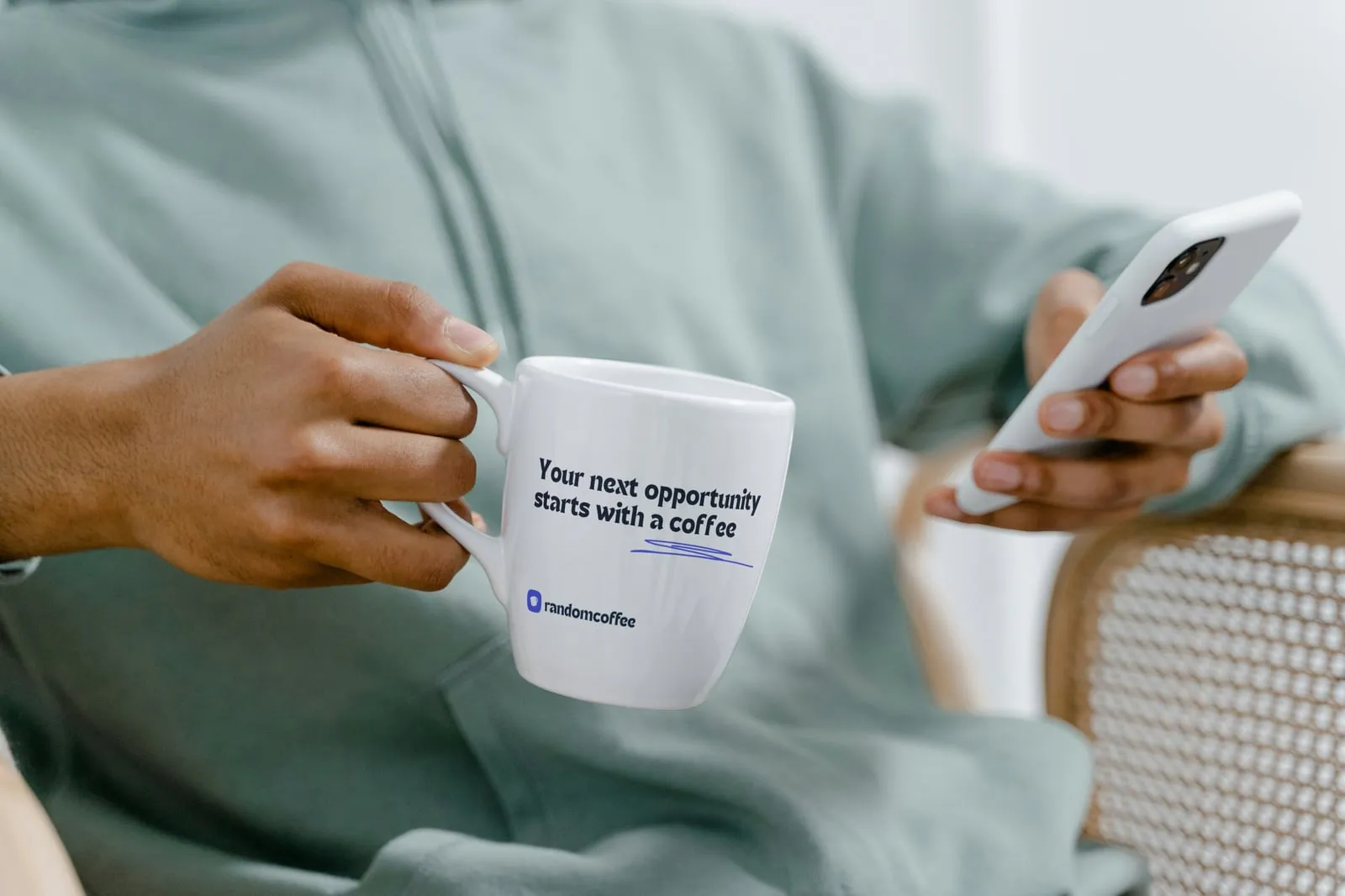 A person holding a RandomCoffee mug with the tagline Your next opportunity starts with a coffee